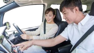 男性指導員が女性ペーパードライバーへ安全運転の講習を実施している画像。