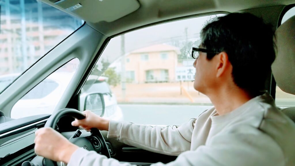 ミラーで後続車を確認する男性