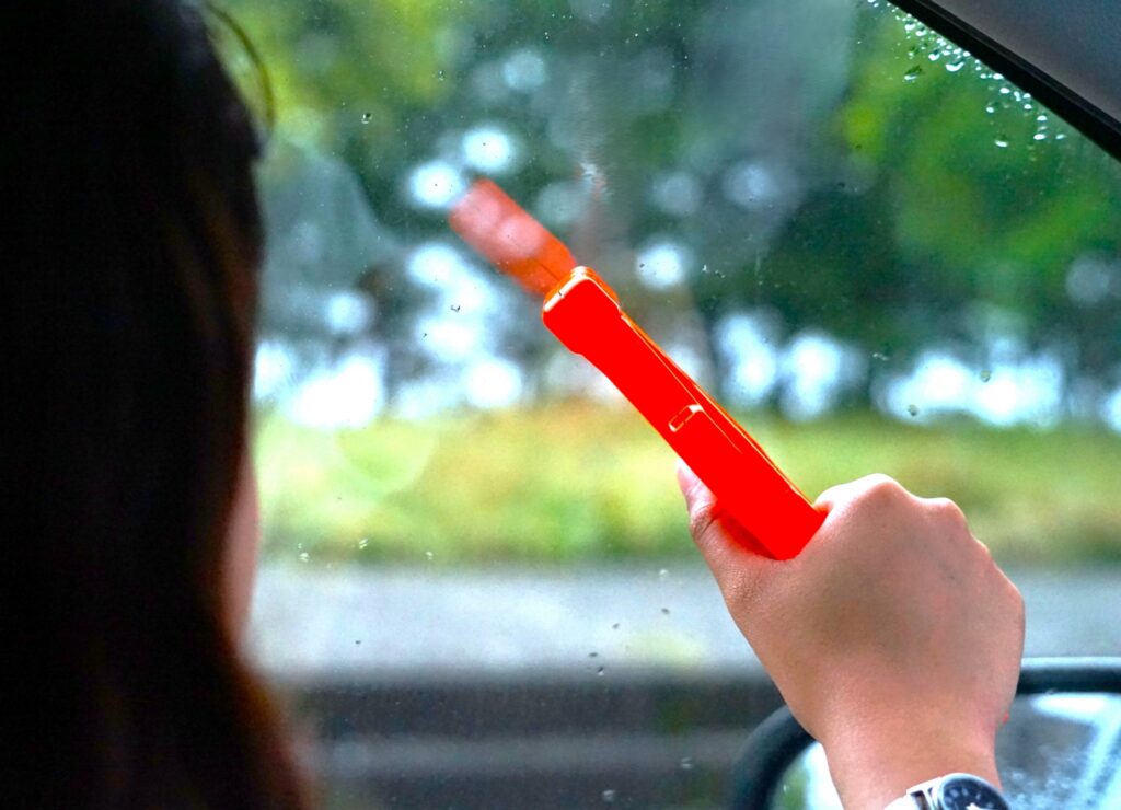 緊急時脱出用ハンマーで窓を破ろうとする女性